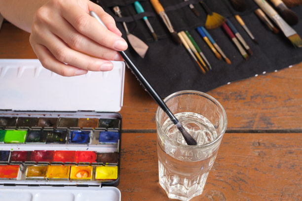 艺术家把画笔蘸到一杯水里图片下载
