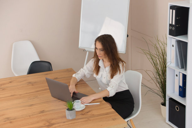 年轻的女商人女商人使用电脑看屏幕，工作在互联网上，坐在办公桌旁，工作场所图片下载