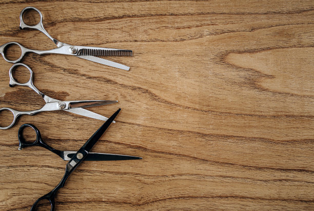 在木制桌子上方理发剪刀的顶部视图。理发店背景与复制空间。图片下载