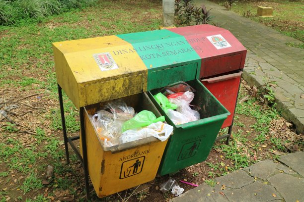 公园中央三个绿色、黄色和红色的垃圾桶图片下载