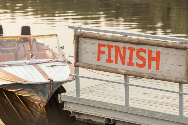 一个夏天的傍晚，一艘油漆剥落的旧船在码头的水面上漂着，船头对着我们图片下载