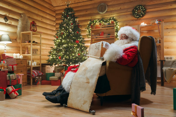 圣诞老人坐在扶手椅上，手里拿着一卷古老的纸卷图片下载