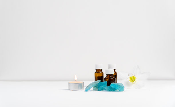 海盐、花、蜡烛和香油装在白色背景的瓶子里。图片下载
