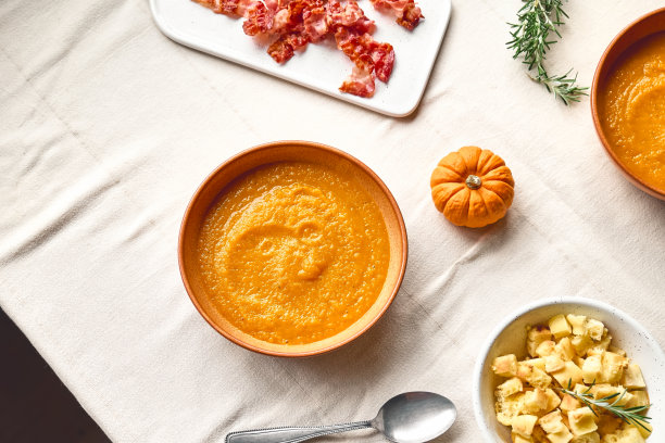 南瓜奶油汤配烤培根和面包丁放在泥盘里，铺上亚麻布桌布。秋天蔬菜奶油汤泥。季节性的饮食健康。图片下载