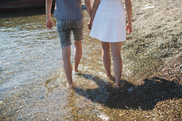 年轻男女手牵着手，赤脚在水上行走图片下载