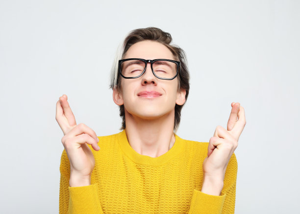 迷人的白人男子举起双手，手指交叉，微笑的肖像图片下载