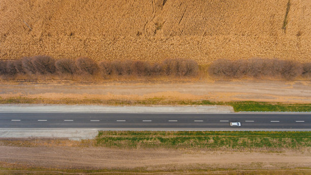 柏油路沿着田野，从空中可以看到道路。俯瞰风景。dron摄影。图片下载