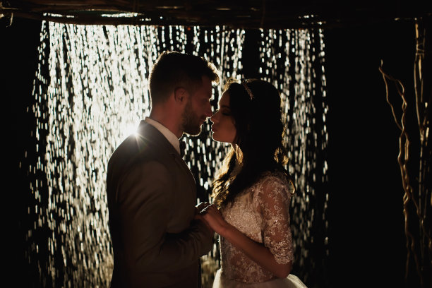 新婚夫妇的浪漫爱情，婚礼的背景是夜空和雨点。新郎和新娘站在雨中拱门的背景上。图片下载