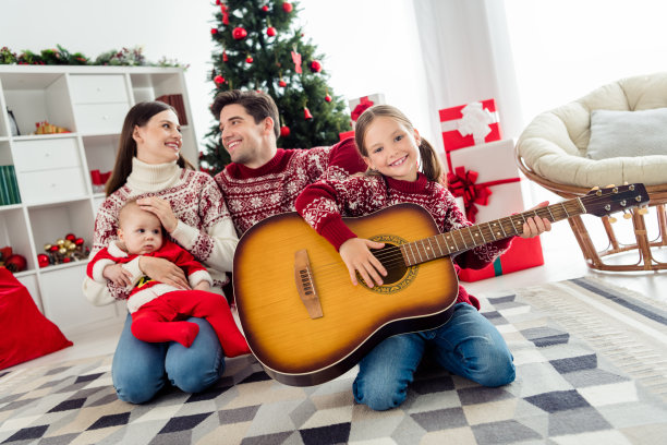 全身照片年轻快乐的家庭快乐积极的微笑小女孩弹吉他装饰节日室内图片下载