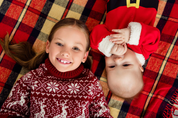 上图是孩子们的照片，哥哥妹妹躺在装饰的圣诞家里穿毛衣的格子微笑服装图片下载