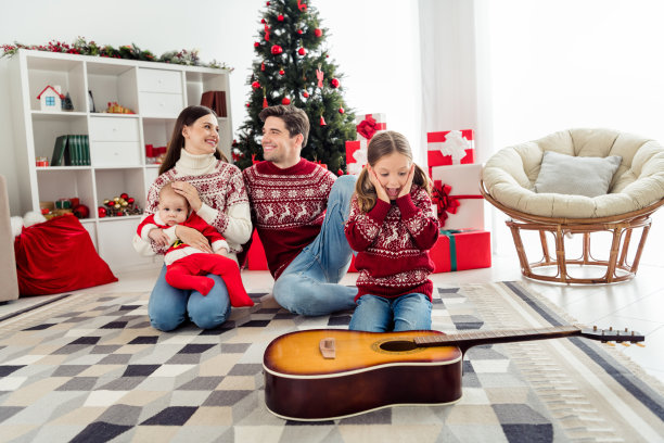 全尺寸照片的妻子丈夫已婚的人童年的圣诞节吉他礼物圣诞树在室内的房子里的家图片下载