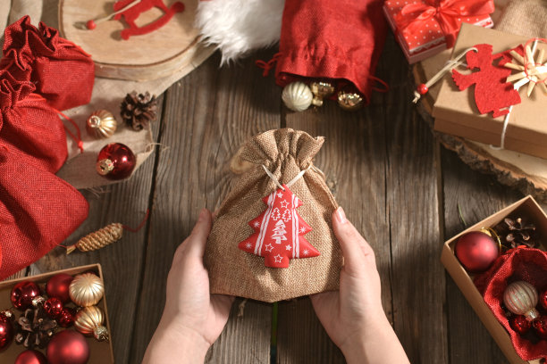 女人的手拿着圣诞礼物放在木桌上，旁边是其他玩具和礼物。真实的圣诞特写照片。为假期做准备。工艺礼品。DIY。出现。舒适的在家度假图片下载