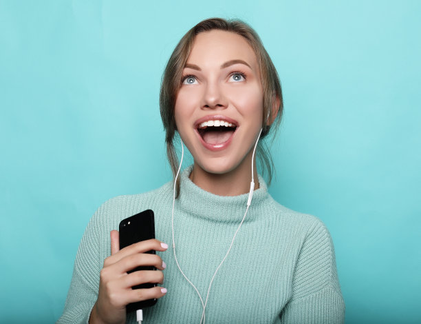 美丽的年轻女子戴着耳机听音乐图片下载