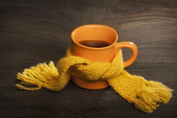 在木制背景上围着围巾的治疗杯图片下载