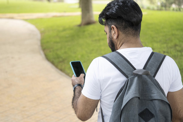 一个拉丁男人背着背包看手机的照片图片下载