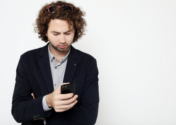 微笑的年轻人拿着智能手机看着它图片下载