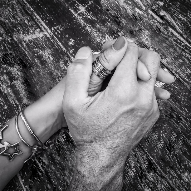 近距离观察男人和女人的手交织在一张旧木桌上。图片下载