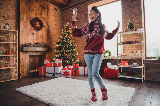 无忧无虑的照片，时髦女士拿着酒杯，享受圣诞晚会的舞蹈，穿套衫在室内装饰的家图片下载