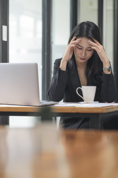 压力和疲倦的年轻女商人头痛在工作场所。图片下载