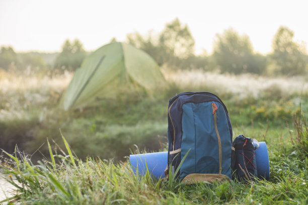 运动背包与地毯关于旅游帐篷的背景上的自然和森林。图片下载