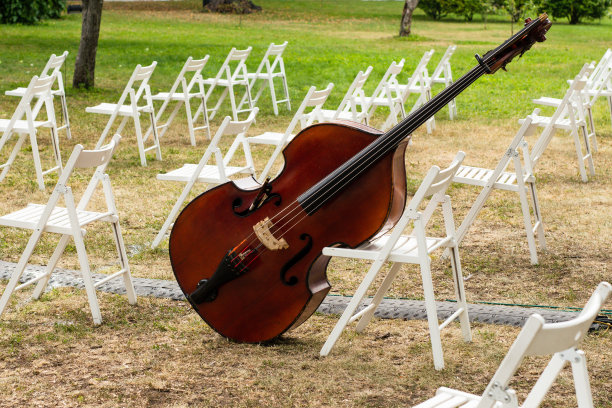 一个大提琴周围的白色木椅在户外活动，没有人。图片下载
