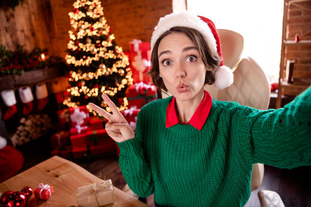 有趣的照片魔术黑发女士做自拍戴帽子绿色毛衣在舒适的房间晚上图片下载