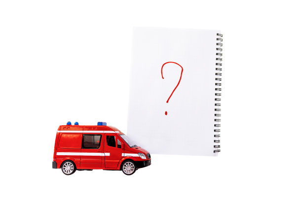 一辆红色的玩具救护车或其他紧急车辆，旁边有一个写着问号的笔记本。孤立的白色背景。放置你的文本。图片下载