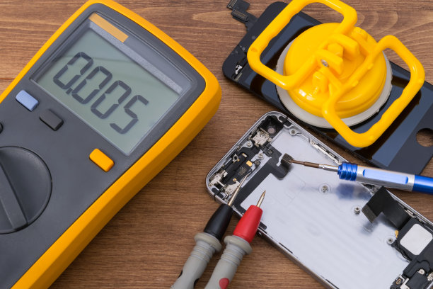 在木制的桌子上，有一台检测智能手机维修和更换损坏部件过程中出现故障的测试仪图片下载