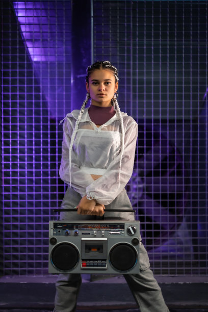 年轻女孩与白色辫子与一个立体声录音机在一个城市的背景，紫色的灯光，80年代风格，复古摄影，垂直照片图片下载