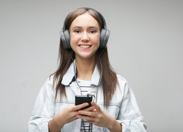 美丽的年轻女子听音乐耳机与智能手机图片下载