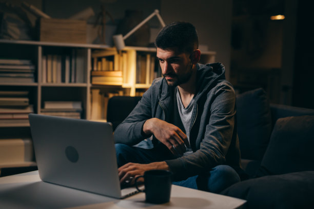 一个男人在家里用笔记本电脑工作到深夜图片下载