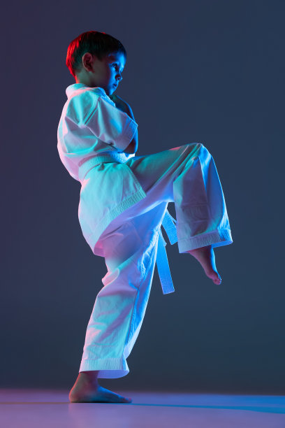 全长肖像的体育小男孩训练武术孤立的梯度蓝色背景在霓虹灯图片下载