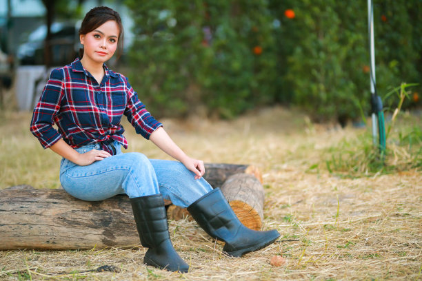 女牛仔的画像。美丽的年轻亚洲女子园丁在红色格子衬衫在夏天日落。图片下载