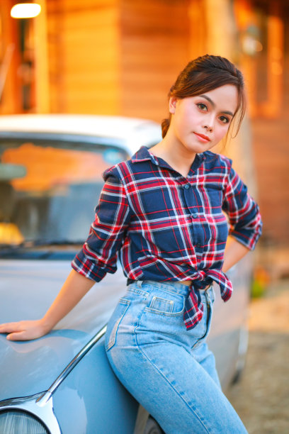 女牛仔的画像。美丽的年轻亚洲女子园丁在红色格子衬衫在夏天日落。图片下载