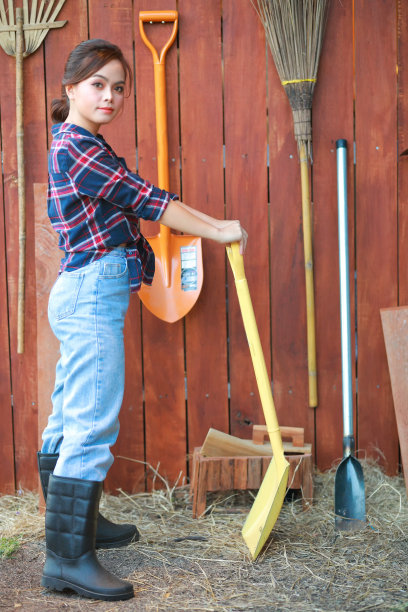 女牛仔的画像。美丽的年轻亚洲女子园丁在红色格子衬衫在夏天日落。图片下载