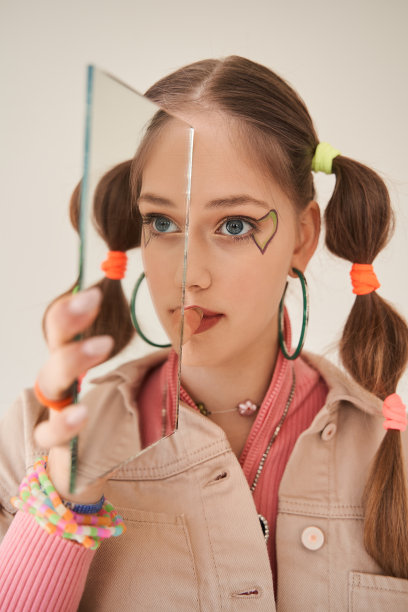 少女在明亮的样子与镜子在摄影棚拍照期间摆姿势图片下载