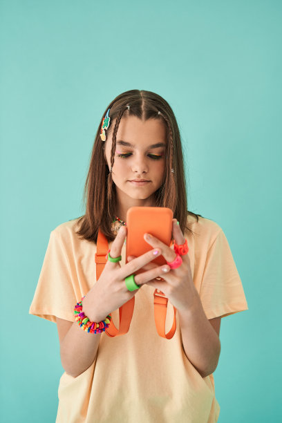 青春期前的少女独自站在一边用智能手机发短信图片下载