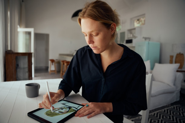 白人女性时装设计师坐在家里办公设计师服装上的数字平板电脑图片下载