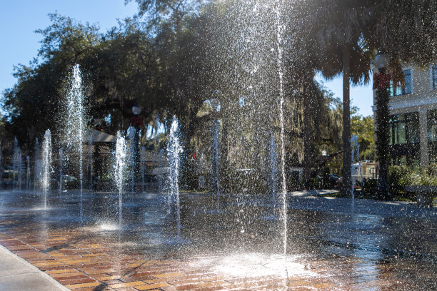 水柱在阳光下喷洒在城镇的飞溅垫图片下载