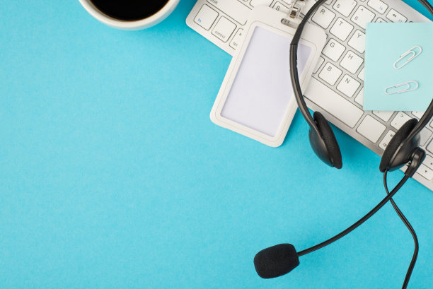 Top view照片的杯子咖啡剪辑粘贴注意id卡持有人和黑色耳机与麦克风在白色键盘上孤立的浅蓝色背景与空白空间图片下载