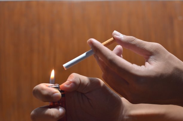 在木制背景下，男性手握香烟的姿势图片下载