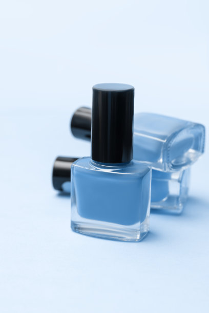 三个蓝色的指甲油瓶子在粉红色的背景上。三个蓝色的指甲油瓶子一个放在另一个上面。副本的空间。图片下载