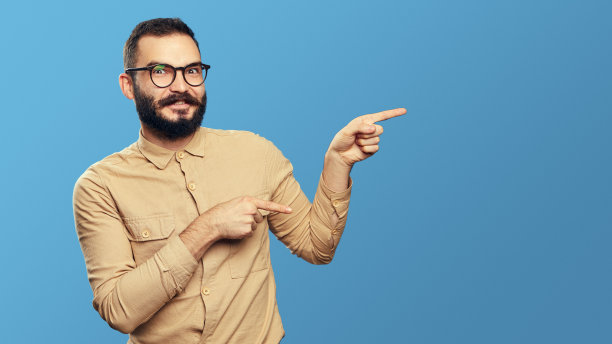 英俊的留胡子的潮人用食指指着旁边的空地图片下载