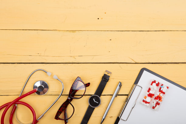工作场所的听诊器等用品摆放在黄色的木桌上图片下载