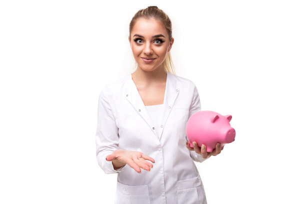 照片的一个美丽的漂亮的有吸引力的积极微笑年轻的金发女人，马尾辫和化妆在一个白色的护士拿着一个粉红色的小猪存钱罐孤立在白色的背景上，自由和复制空间的文本图片下载