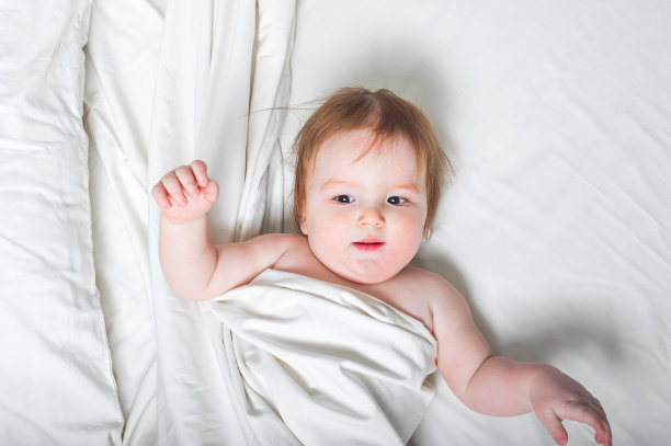 红发小孩在床上笑。婴儿发育概念，幼儿休息睡眠，出牙，腹痛。图片下载