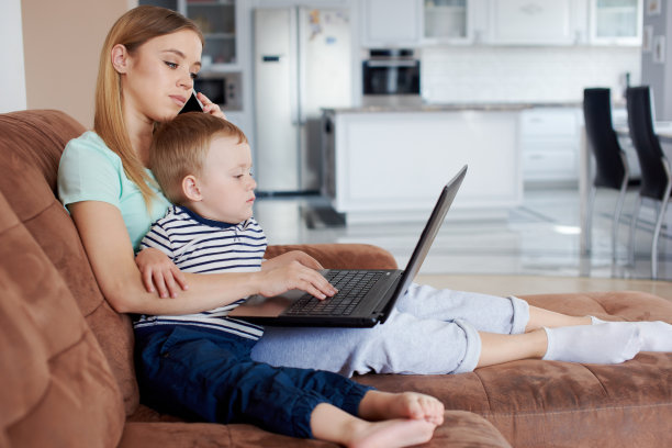 忙碌的母亲抱着儿子讲电话图片下载