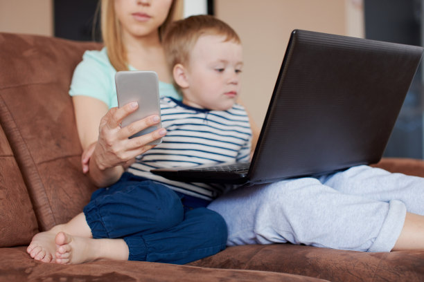 近母亲持有智能手机和使用笔记本电脑与她的宝宝图片下载