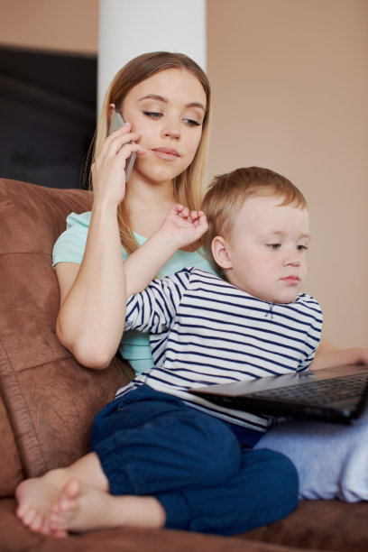 忙碌的母亲抱着儿子讲电话图片下载