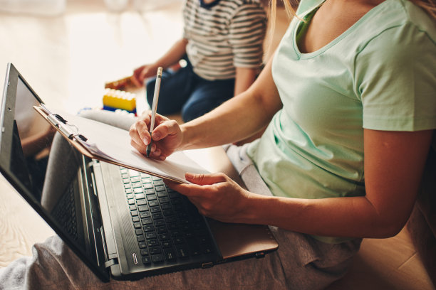 年轻女子带着孩子在笔记本电脑上学习，做笔记图片下载